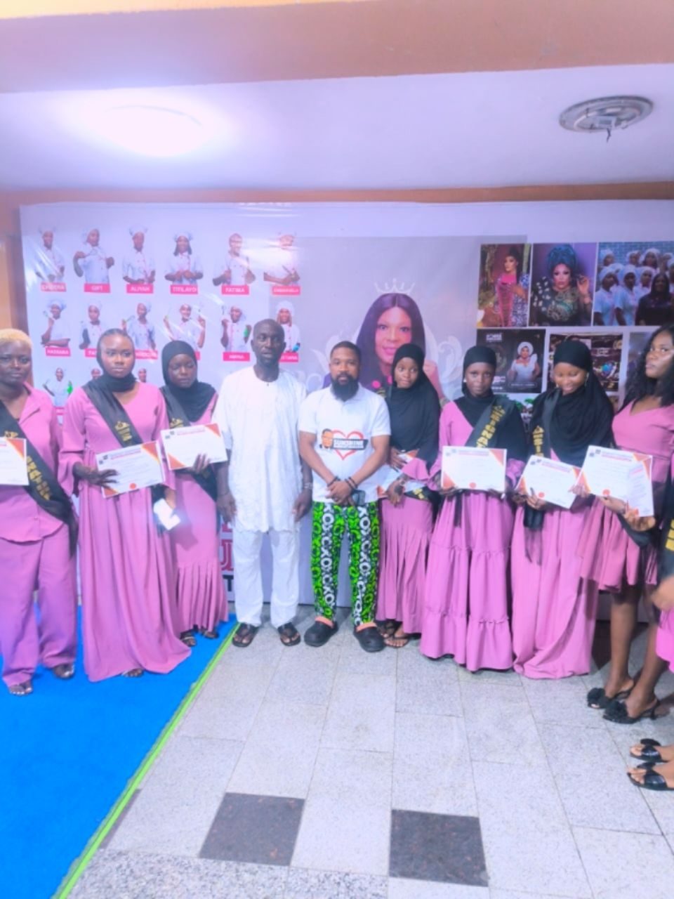 Graduating trainees in pink gowns with certificates