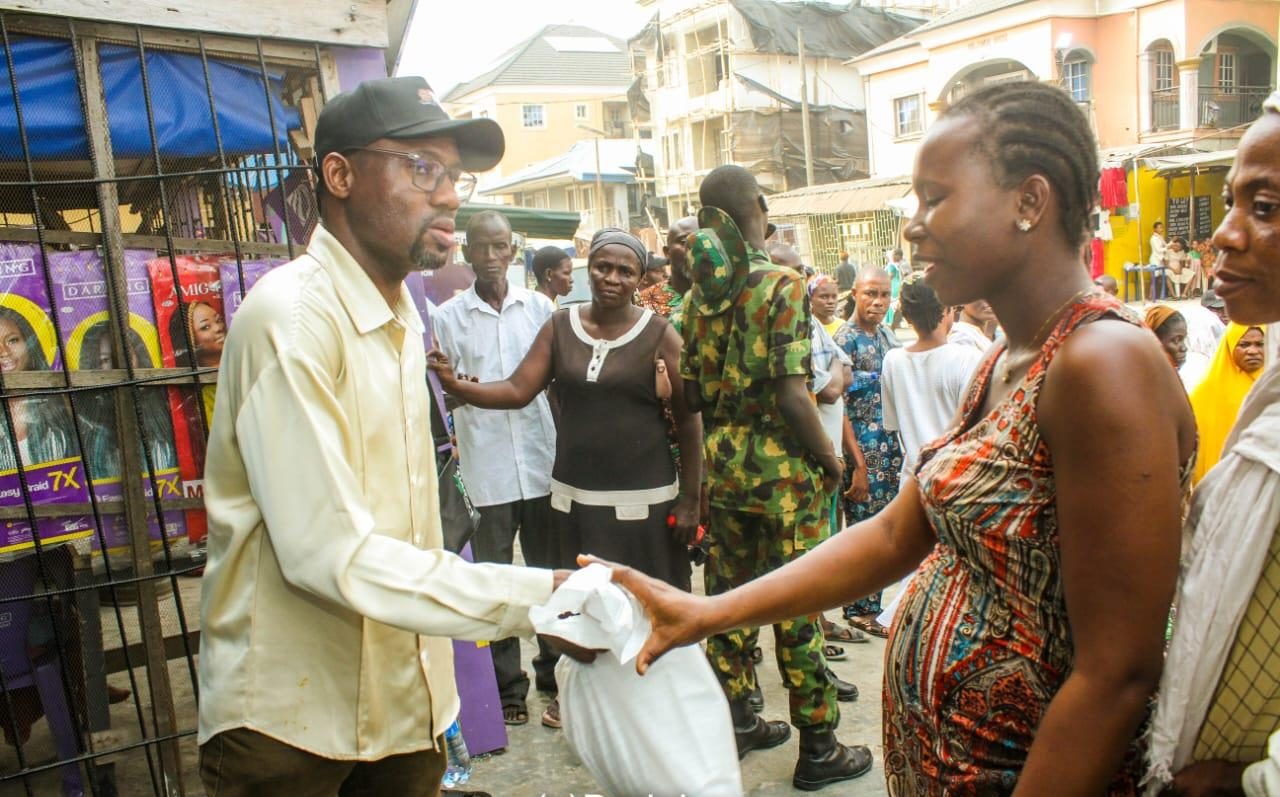 Dr. Arogundade Samsondeen hands a food pack to a young woman