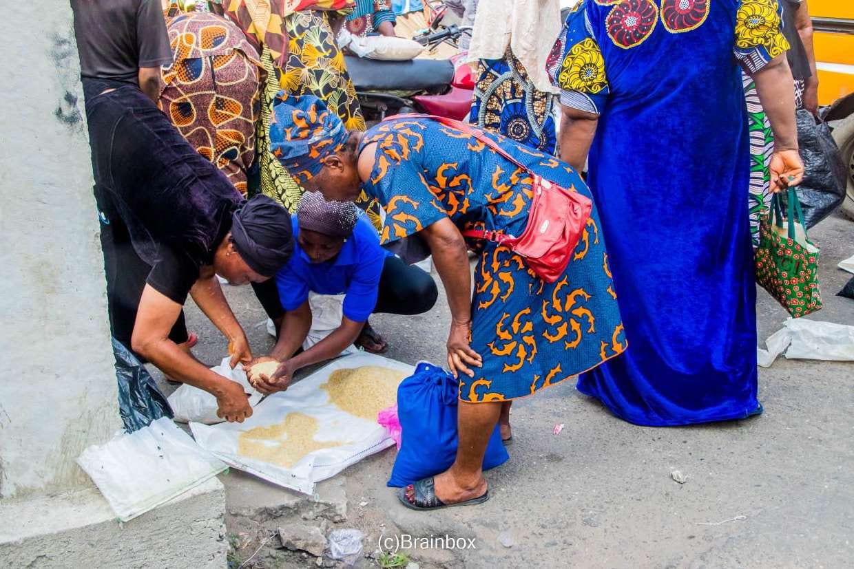 A woman packs rice into bags on the ground