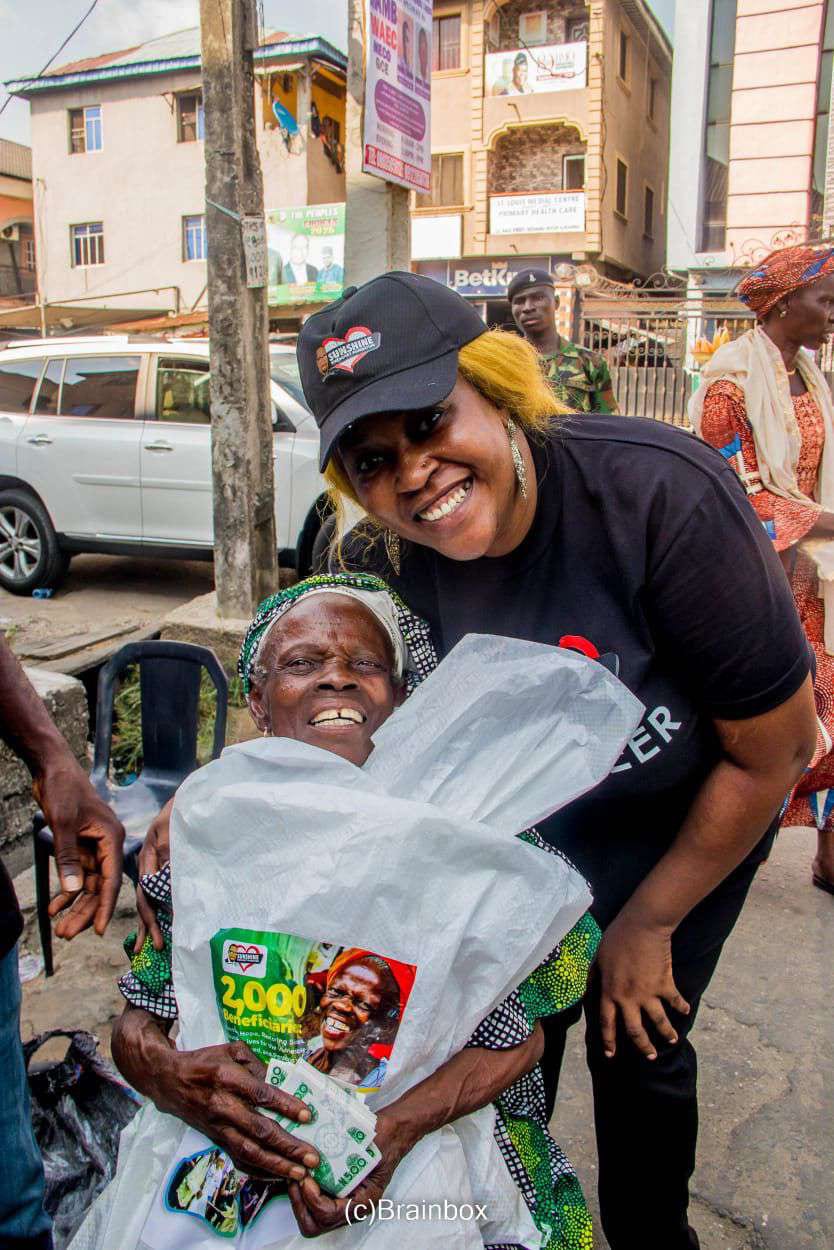 A volunteer in the SKF shirt hugs an elderly woman holding her food pack