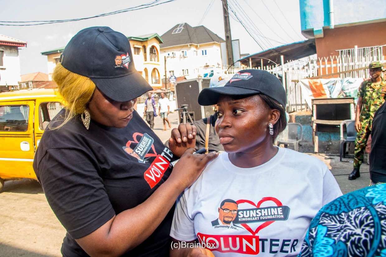 A volunteer helps another put on the SKF volunteer shirt